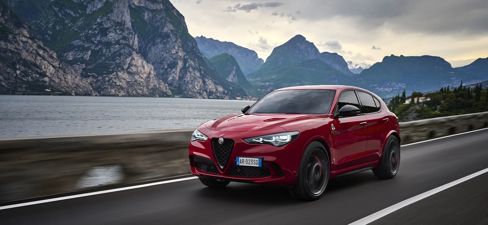 Alfa Romeo Stelvio Quadrifoglio in movimento su una strada di montagna lungo un lago
